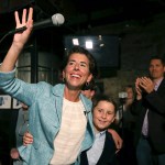 Incumbent Democratic Rhode Island Gov. Gina Raimondo waves to supporters, alongside her son, Thompson, at her primary night victory party, Wednesday, Sept. 12, 2018, in Providence, R.I. (AP Photo/Elise Amendola)