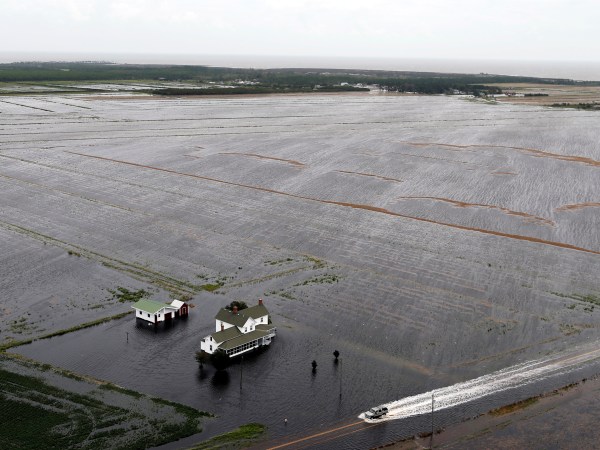 A pickup truck drives on a flooded road past a farm house that is surrounded by flooded fields in Hyde County, NC., Saturday, Sept. 15, 2018.  (AP Photo/Steve Helber)