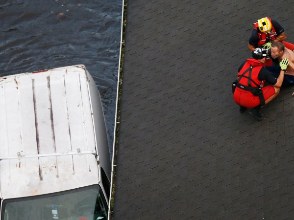 US Coast Guard rescue swimmer Samuel Knoeppel, top, and Randy Haba, bottom left, talk to Willie Schubert of Pollocksville, N.C., as he is rescued from a rooftop in Pollocksville, NC., Monday, Sept. 17, 2018.  (AP Photo/Steve Helber)