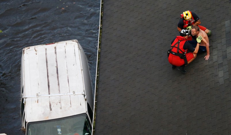 US Coast Guard rescue swimmer Samuel Knoeppel, top, and Randy Haba, bottom left, talk to Willie Schubert of Pollocksville, N.C., as he is rescued from a rooftop in Pollocksville, NC., Monday, Sept. 17, 2018.  (AP Photo/Steve Helber)