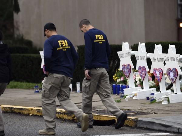 Members of the FBI walk past a memorial outside the Tree of Life synagogue after a shooting there left 11 people dead in the Squirrel Hill neighborhood of Pittsburgh on October 27. - Mourners held an emotional vigil Sunday for victims of a fatal shooting at a Pittsburgh synagogue, an assault that saw a gunman who said he "wanted all Jews to die" open fire on a mostly elderly group. Americans had earlier learned the identities of the 11 people killed in the brutal assault at the Tree of Life synagogue, including 97-year-old Rose Mallinger and couple Sylvan and Bernice Simon, both in their 80s.Nine of the victims were 65 or older. (Photo by Brendan SMIALOWSKI / AFP)        (Photo credit should read BRENDAN SMIALOWSKI/AFP/Getty Images)