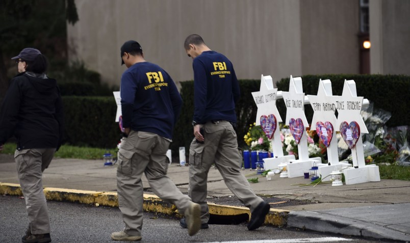 Members of the FBI walk past a memorial outside the Tree of Life synagogue after a shooting there left 11 people dead in the Squirrel Hill neighborhood of Pittsburgh on October 27. - Mourners held an emotional vigil Sunday for victims of a fatal shooting at a Pittsburgh synagogue, an assault that saw a gunman who said he "wanted all Jews to die" open fire on a mostly elderly group. Americans had earlier learned the identities of the 11 people killed in the brutal assault at the Tree of Life synagogue, including 97-year-old Rose Mallinger and couple Sylvan and Bernice Simon, both in their 80s.Nine of the victims were 65 or older. (Photo by Brendan SMIALOWSKI / AFP)        (Photo credit should read BRENDAN SMIALOWSKI/AFP/Getty Images)