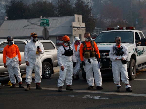 First responders look on as the motorcade of President Donald Trump visits a neighborhood impacted by the wildfires, Saturday, Nov. 17, 2018, in Paradise, Calif. (AP Photo/Evan Vucci)
