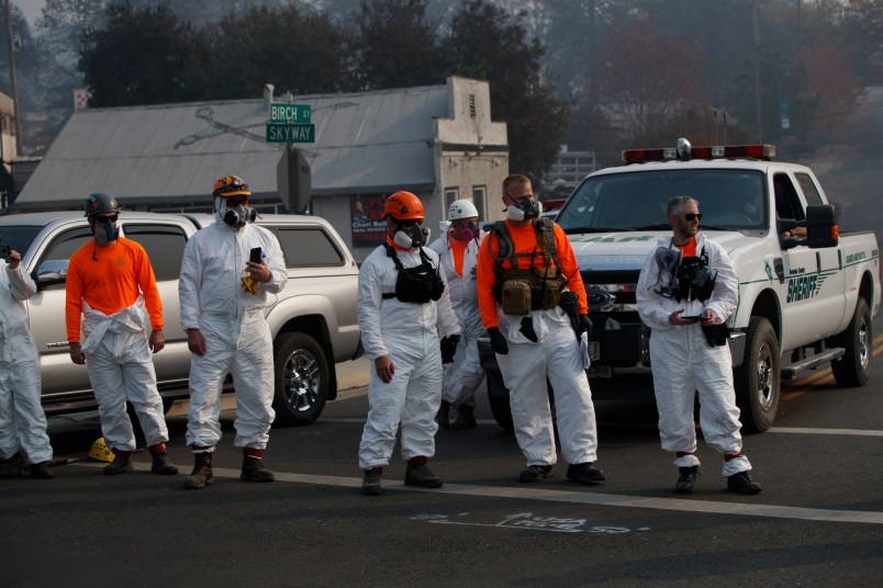 First responders look on as the motorcade of President Donald Trump visits a neighborhood impacted by the wildfires, Saturday, Nov. 17, 2018, in Paradise, Calif. (AP Photo/Evan Vucci)
