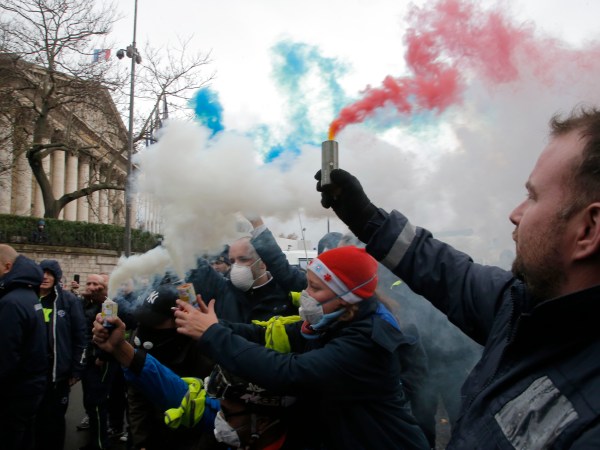 Ambulance workers hold flares outside the National Assembly in Paris, Monday, Dec. 3, 2018. Ambulance workers took to the streets and gathered close to the National Assembly in downtown Paris to complain about changes to working conditions as French Prime Minister Edouard Philippe is holding crisis talks with representatives of major political parties in the wake of violent anti-government protests that have rocked Paris. (AP Photo/Michel Euler)