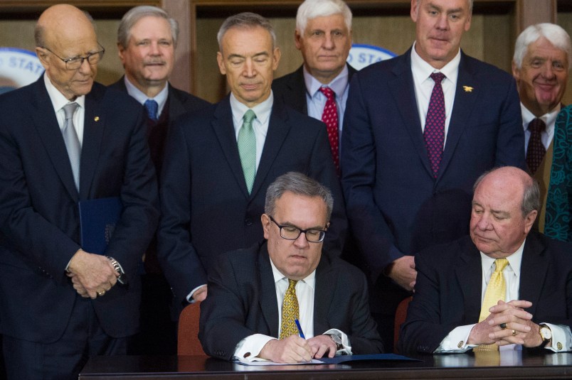 Acting EPA Administrator Andrew Wheeler, seated left, signs an order withdrawing federal protections for countless waterways and wetlands, as Assistant Secretary of the Army for Civil Works Rickey "RD" James, seated right, looks on, at EPA headquarters in Washington, Tuesday, Dec. 11, 2018. Look on behind are Senate Agriculture Committe Chairman Pat Ross, R-Kansas, left, and Secretary of the Interior Ryan Zinke, second from right.   (AP Photo/Cliff Owen)