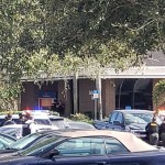 Law enforcement officials take cover outside the SunTrust Bank branch, Wednesday, Jan. 23, 2019, in Sebring, Fla. Authorities say they've arrested a man who fired shots inside the Florida bank. (Highlands NewsSun via AP)