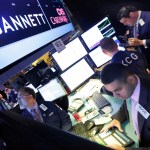 FILE - In this Aug. 5, 2014, file photo, specialist Michael Cacace, foreground right, works at the post that handles Gannett on the floor of the New York Stock Exchange.  Gannett is walking away from its takeover attempt at Tronc, the publisher of the Los Angeles Times, Chicago Tribune and other major dailies. Shares of Gannett Co., publisher of USA Today, are surging more than 8 percent in premarket trading Tuesday, Nov. 1, 2016.  (AP Photo/Richard Drew, File)