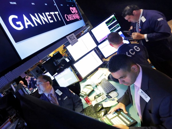 FILE - In this Aug. 5, 2014, file photo, specialist Michael Cacace, foreground right, works at the post that handles Gannett on the floor of the New York Stock Exchange.  Gannett is walking away from its takeover attempt at Tronc, the publisher of the Los Angeles Times, Chicago Tribune and other major dailies. Shares of Gannett Co., publisher of USA Today, are surging more than 8 percent in premarket trading Tuesday, Nov. 1, 2016.  (AP Photo/Richard Drew, File)
