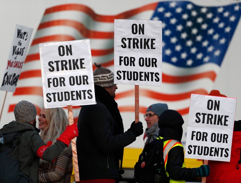 Teachers carry placards as they walk a picket line outside South High School early Monday, Feb. 11, 2019, in Denver. The walkout is the first for teachers in Denver since 1994 and centers on base pay. (AP Photo/David Zalubowski)