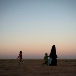 A woman walks with her children at a U.S.-backed Syrian Democratic Forces (SDF) screening area after being evacuated out of the last territory held by Islamic State militants, in the desert outside Baghouz, Syria, Friday, March 1, 2019. (AP Photo/Felipe Dana)
