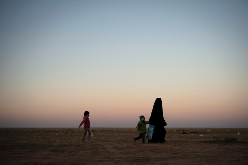A woman walks with her children at a U.S.-backed Syrian Democratic Forces (SDF) screening area after being evacuated out of the last territory held by Islamic State militants, in the desert outside Baghouz, Syria, Friday, March 1, 2019. (AP Photo/Felipe Dana)