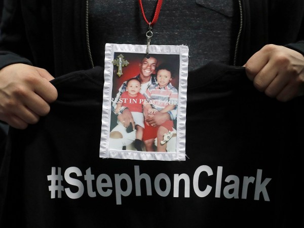A mourner holds up a photo of police shooting victim Stephon Clark during the funeral services for Clark at Bayside Of South Sacramento Church in Sacramento, Calif., Thursday, March 29, 2018. Clark, who was unarmed, was shot and killed by Sacramento Police Officers, Sunday, March 18, 2018. (AP Photo/Jeff Chiu, Pool)