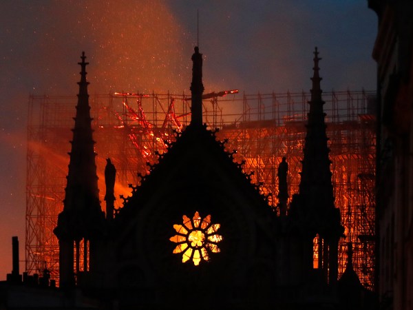 Flames and smoke rise from Notre Dame cathedral as it burns in Paris, Monday, April 15, 2019. Massive plumes of yellow brown smoke is filling the air above Notre Dame Cathedral and ash is falling on tourists and others around the island that marks the center of Paris. (AP Photo/Thibault Camus)