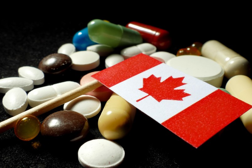 Canadian flag with lot of medical pills isolated on black background