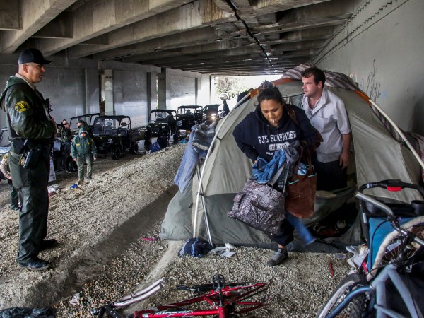 PICO RIVERA, CA JANUARY 05, 2016 ---  Los Angeles sheriff deputy Michael Galvan, left, warns a couple living under Freeway 5 bridge along San Gabriel River in Pico Rivera. LASD deputies ventured out in pouring rain looking for homeless encampments along river to warn inhabitants  about danger of flooding and to provide them information of nearby shelters. (Irfan Khan / Los Angeles Times)