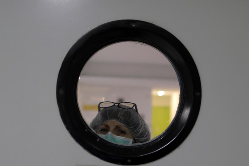 A health worker wearing a face mask looks out of from a window at a nursing homes in Madrid, Spain, Tuesday, March 31, 2020. The new coronavirus causes mild or moderate symptoms for most people, but for some, especially older adults and people with existing health problems, it can cause more severe illness or death. (AP Photo/Manu Fernandez)