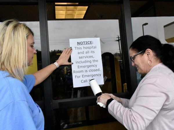 Carol Talkington helps Terri Bonasso tape a notice on the Emergency room door following a vigil at the closing of Fairmont Regional Medical Center on March 19, 2020.