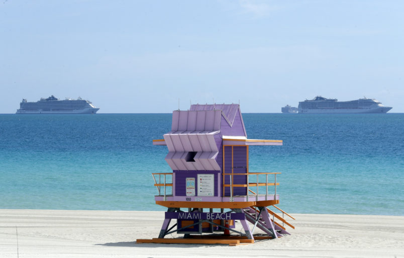 Two cruise ships are shown anchored offshore past a lifeguard tower, Tuesday, March 31, 2020, in Miami Beach, Fla. (AP Photo/Wilfredo Lee)