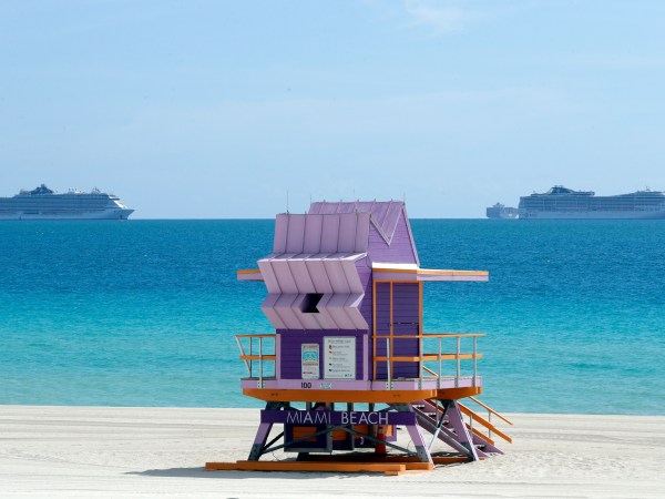 Two cruise ships are shown anchored offshore past a lifeguard tower, Tuesday, March 31, 2020, in Miami Beach, Fla. (AP Photo/Wilfredo Lee)