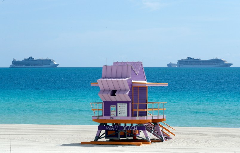 Two cruise ships are shown anchored offshore past a lifeguard tower, Tuesday, March 31, 2020, in Miami Beach, Fla. (AP Photo/Wilfredo Lee)