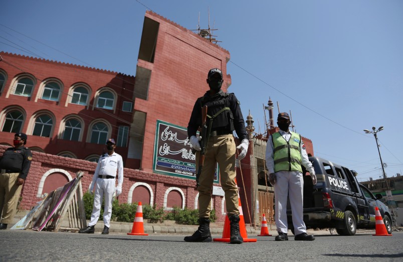 Police officers stand guard outside a mosque during a lockdown to contain the coronavirus in Karachi, Pakistan, Friday, March, 3, 2020. Some mosques were allowed to remain open in Pakistan on Friday, the Muslim sabbath when adherents gather for weekly prayers, even as the coronavirus pandemic spread and much of the country had shut down. (AP Photo/Fareed Khan)