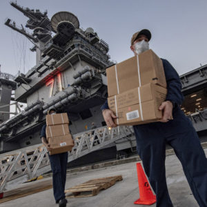 ** HOLD FOR STORY ** In this April 7, 2020, photo released by the U.S. Navy, sailors assigned to the aircraft carrier USS Theodore Roosevelt move ready to eat meals for sailors who have tested negative for COVID-19 at Naval Base Guam who were being taken to local hotels in an effort to implement social distancing. (Mass Communication Specialist 1st Julio Rivera/U.S. Navy via AP)