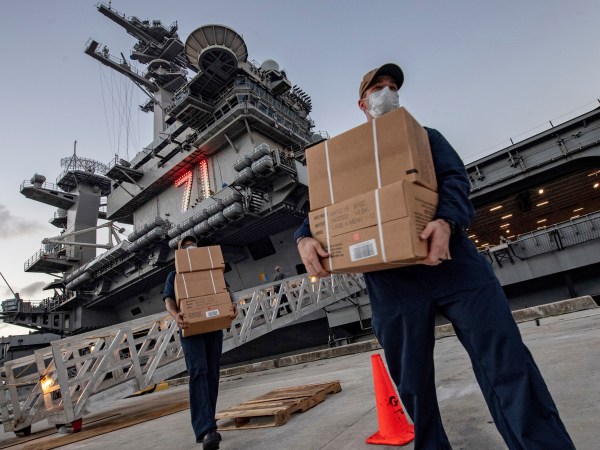 ** HOLD FOR STORY ** In this April 7, 2020, photo released by the U.S. Navy, sailors assigned to the aircraft carrier USS Theodore Roosevelt move ready to eat meals for sailors who have tested negative for COVID-19 at Naval Base Guam who were being taken to local hotels in an effort to implement social distancing. (Mass Communication Specialist 1st Julio Rivera/U.S. Navy via AP)
