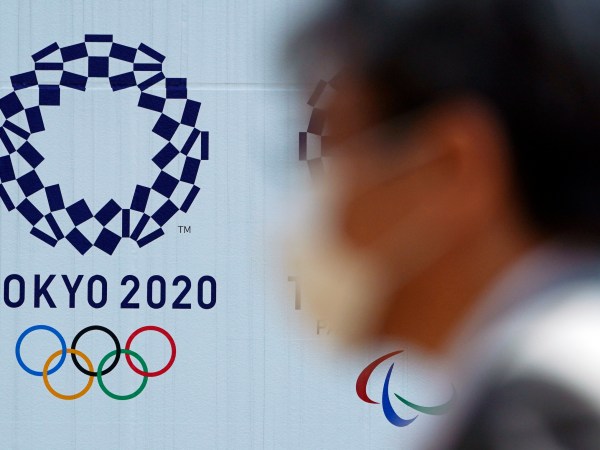 A man wearing a protective face mask walks near the Tokyo 2020 Olympics Thursday, April 2, 2020, in Tokyo. The new coronavirus causes mild or moderate symptoms for most people, but for some, especially older adults and people with existing health problems, it can cause more severe illness or death. (AP Photo/Eugene Hoshiko)