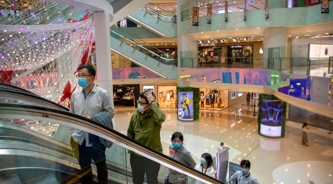 ***HOLD FOR CHINA GDP STORY***In this April 15, 2020 photo, people wear facemasks to protect against the spread of the new coronavirus cleans as they ride an escalator at a shopping mall in Beijing. (AP Photo/Mark Schiefelbein)