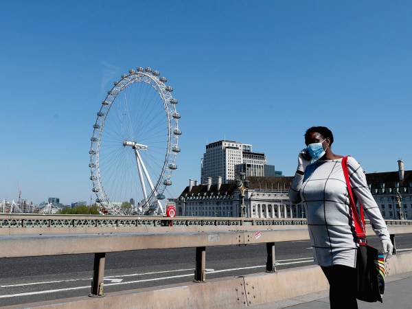 A woman wearing a protection mask walks over Westminster Bridge in London, Wednesday April 22, 2020 during the COVID-19 lockdown. (AP Photo/Frank Augstein)