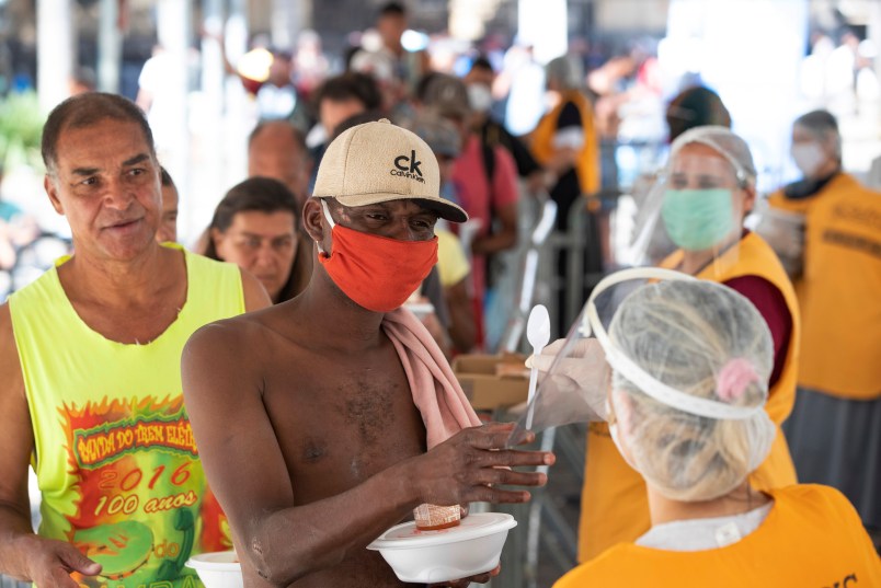 Volunteers from a christian church give food to homeless people during a quarantine imposed by the state government to help stop the spread of the new coronavirus in Sao Paulo, Brazil, Monday, April 27, 2020. (AP Photo/Andre Penner)