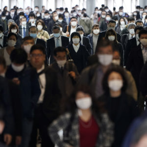 FILE - In this file April 27, 2020 photo, a station passageway is crowded with commuters wearing face mask in Tokyo. Under Japan’s coronavirus state of emergency, people have been asked to stay home. Many are not. Many still have to commute to their jobs despite risks of infection, while others continue to dine out, picnic in parks and crowd into grocery stores with scant regard for social distancing. (AP Photo/Eugene Hoshiko, File)