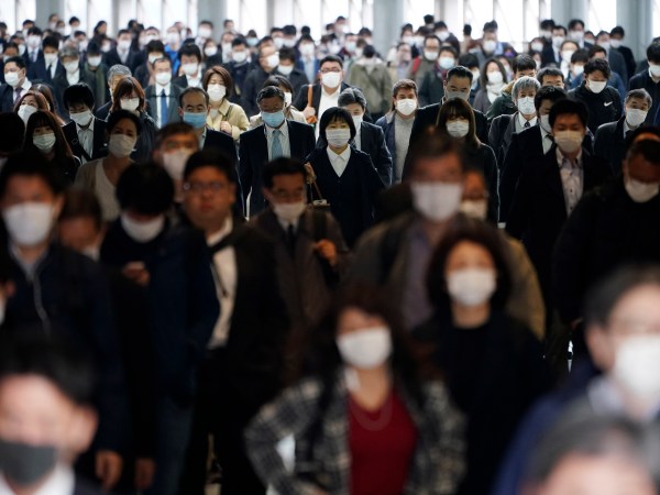 FILE - In this file April 27, 2020 photo, a station passageway is crowded with commuters wearing face mask in Tokyo. Under Japan’s coronavirus state of emergency, people have been asked to stay home. Many are not. Many still have to commute to their jobs despite risks of infection, while others continue to dine out, picnic in parks and crowd into grocery stores with scant regard for social distancing. (AP Photo/Eugene Hoshiko, File)