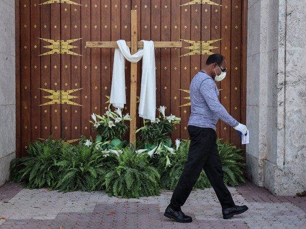 An unidentified man passes the closed front doors of St. Mary's Cathedral as houses of worship closed their doors, but telecast their Sunday Easter services via social media, as large social and religious gatherings are prohibited due to shelter-in-place mandates by local and state governments on Easter Sunday, April 12, 2020 in Miami, Fla. (Carl Juste/Miami Herald/TNS)