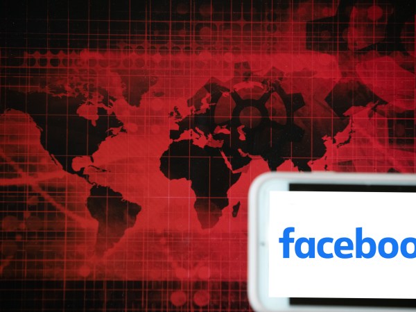 The logo of social media giant Facebook is seen on a screen of a phone next to a red illustration of world and financial markets in Frankfurt, Germany, on April 14, 2020. It is one of the companies that might gain most from the lockdown. (Photo Illustration by Alexander Pohl/NurPhoto)