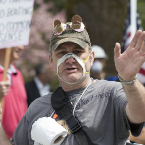 OLYMPIA, WA - APRIL 19: A man wearing a cutout mask gathered with hundreds of othersat a rally titled “Hazardous Liberty! Defend the Constitution!” to protest the stay-at-home order, at the Capitol building on April 19, 2020 in Olympia, Washington. Washington state Governor Jay Inslee instituted the order last month to slow the spread COVID-19. Many who attended did not follow social distancing guidelines or wear masks but were there to support their right to assemble. They advocated that people should be allowed to go back to work. (Photo by Karen Ducey/Getty Images)