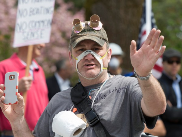 OLYMPIA, WA - APRIL 19: A man wearing a cutout mask gathered with hundreds of othersat a rally titled “Hazardous Liberty! Defend the Constitution!” to protest the stay-at-home order, at the Capitol building on April 19, 2020 in Olympia, Washington. Washington state Governor Jay Inslee instituted the order last month to slow the spread COVID-19. Many who attended did not follow social distancing guidelines or wear masks but were there to support their right to assemble. They advocated that people should be allowed to go back to work. (Photo by Karen Ducey/Getty Images)