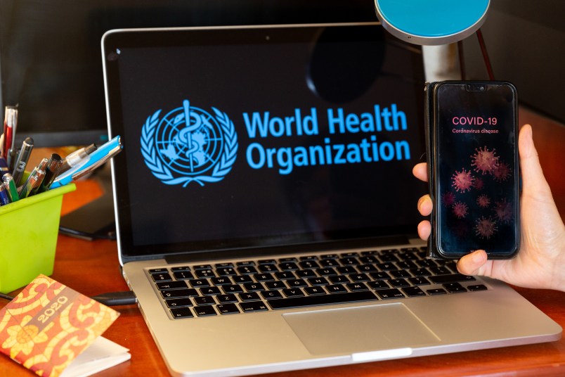 For illustrative purposes a woman holds her mobile phone with a Covid-19 note in front of a computer screen with World Health Organisation logo during Coronavirus pandemic on April 21, 2020. The role of WHO is crucial during epidemics and pandemics. (Photo by Dominika Zarzycka/NurPhoto)