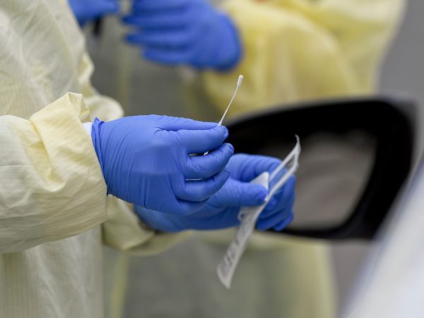 A detail photo of a nasal swab held by a Registered Nurse wearing gloves and a protective gown that she is about to use to do a test on a patient in their car at Penn State Health St. Joseph where they are conducting drive through coronavirus / COVID-19 testing and have taken extra precautions regarding entry to the hospital,  in Bern Township, PA Friday afternoon March 27, 2020.