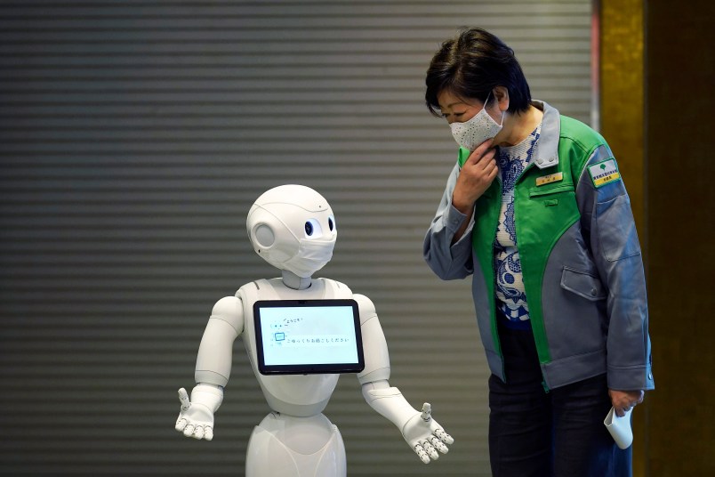 A humanoid robot Pepper with a face mask  greets Tokyo Gov. Yuriko Koike at the lobby of a hotel for the new coronavirus COVID-19 patients with mild symptoms during a media preview in Tokyo Friday, May 1, 2020. Prime Minister Shinzo Abe said Thursday he planned to extend a state of emergency beyond the scheduled end of May 6 because infections are spreading and hospitals are overburdened. (AP Photo/Eugene Hoshiko)
