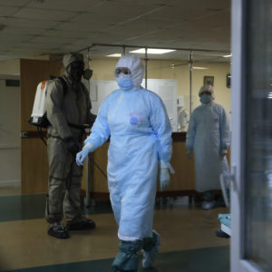 A serviceman of Belarus Ministry of Defence, left, and medical workers wearing protective gear seen at a local hospital in Minsk, Belarus, Tuesday, May 5, 2020. Despite the World Health Organization's call for Belarus to ban public events as coronavirus cases rise sharply, President Alexander Lukashenko says the country will go ahead with a parade to mark the 75th anniversary of the defeat of Nazi Germany. (AP Photo/Sergei Grits)