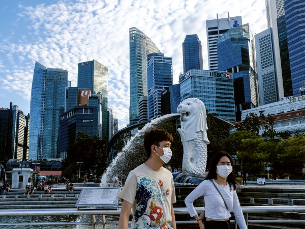 /// In this image taken Saturday, Mar. 14, 2020, a couple wearing face masks walk past the Merlion statue in Singapore. As the virus outbreak spreads ever further, it's becoming clear that some strategies are more likely to succeed in containing it: pro-active efforts to track down and isolate cases, access to basic, affordable public health and clear, reassuring messaging from leaders. (AP Photo/Ee Ming Toh)