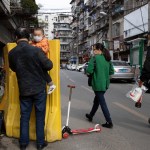 In this photo taken Wednesday, April 1, 2020, residents walk past a sealed off neighborhood in Wuhan in central China's Hubei province. Authorities in Wuhan, the Chinese city where the coronavirus pandemic first broke out, have reportedly launched a plan to test everyone in the city of 11 million people in the next 10 days.  (AP Photo/Ng Han Guan)