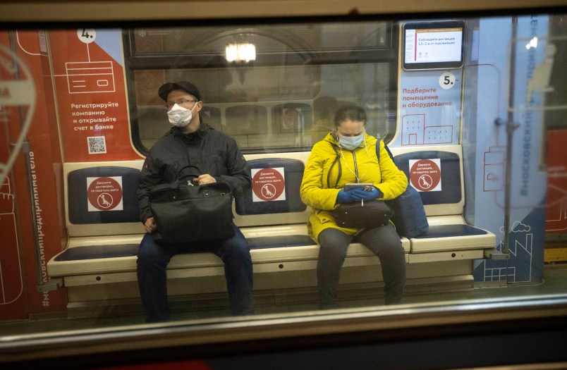People wearing face masks and gloves to protect against coronavirus, observe social distancing guidelines as they ride a carriage in the subway on the escalator in Moscow, Russia, Wednesday, May 13, 2020. Wearing face masks and latex gloves is mandatory for people using Moscow's public transport. President Vladimir Putin declared an end to a partial economic shutdown across Russia due to the coronavirus pandemic, but he said that many restrictions will remain in place. (AP Photo/Alexander Zemlianichenko)