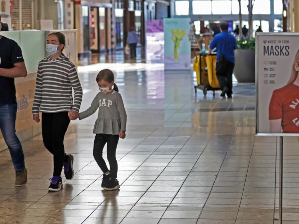 Shoppers walks past a sign encouraging masks at SouthPark Mall, Wednesday, May 13, 2020, in Strongsville, Ohio. Ohio retail businesses reopened Tuesday following a nearly two-month-long shutdown ordered by Gov. Mike DeWine to limit the spread of the coronavirus.  (AP Photo/Tony Dejak)