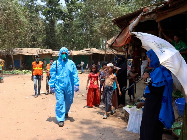 In this April 15, 2020, photograph, a health worker from an aid organization walks wearing a hazmat suit at the Kutupalong Rohingya refugee camp in Cox's Bazar, Bangladesh. There's been little if any coronavirus testing in Cox's Bazar, where more than a million members of Myanmar's Rohingya Muslim minority are packed into the world's largest refugee camp. (AP Photo/Shafiqur Rahman)