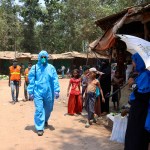 In this April 15, 2020, photograph, a health worker from an aid organization walks wearing a hazmat suit at the Kutupalong Rohingya refugee camp in Cox's Bazar, Bangladesh. There's been little if any coronavirus testing in Cox's Bazar, where more than a million members of Myanmar's Rohingya Muslim minority are packed into the world's largest refugee camp. (AP Photo/Shafiqur Rahman)