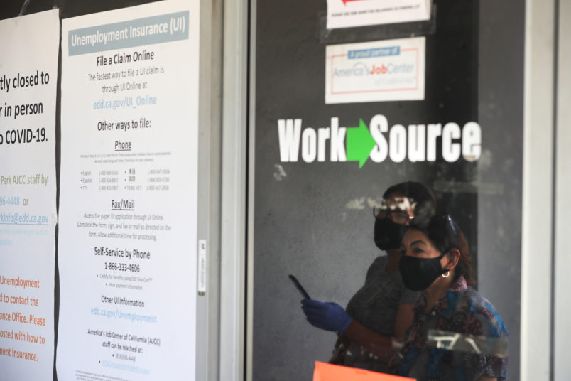 CANOGA PARK, CA - MAY 14: Estella Flores, right, and Maria Mora, left, are reflected in a window as they look for information in front of the closed California State Employment Development Department on Thursday, May 14, 2020 in Canoga Park, CA. (Brian van der Brug / Los Angeles Times)