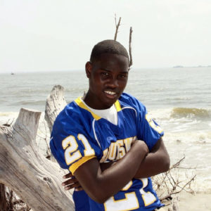 In this 2012 photo provided by Yolanda Richardson, of FuzzyRabbit Fotos, Ahmaud Arbery poses for a senior photo on St. Andrews Beach, Jekyll Island, Ga. Arbery was killed Feb. 23 after a pursuit by a white father and son who armed themselves and gave chase after seeing the 25-year-old black man running in their subdivision. (Yolanda Richardson/FuzzyRabbit Fotos via AP)